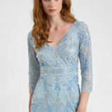 Woman wearing a light blue patterned dress with long sleeves on a white background