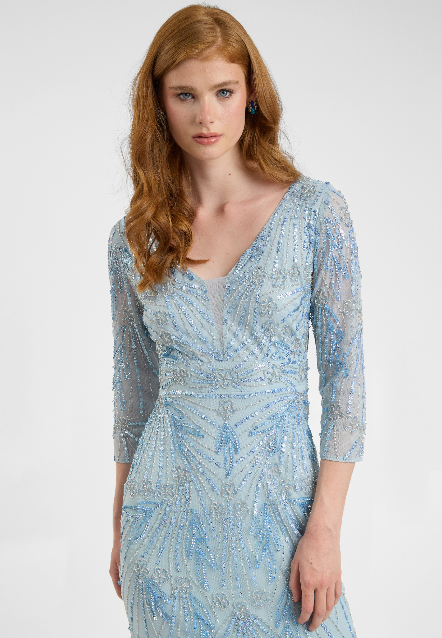 Woman wearing a light blue patterned dress with long sleeves on a white background