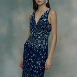 Woman wearing a navy blue floral dress against a gray background