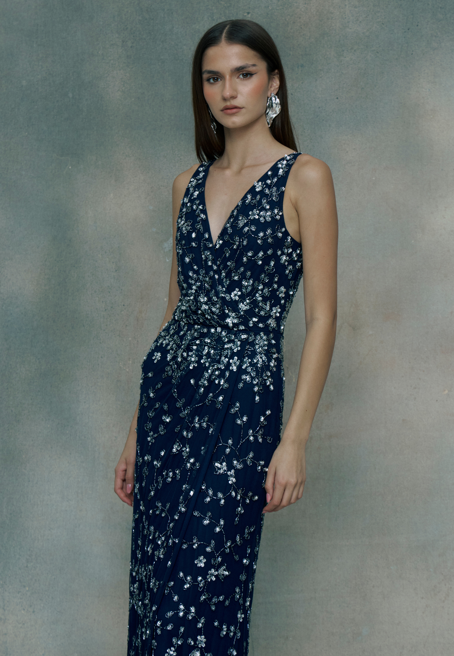 Woman wearing a navy blue floral dress against a gray background