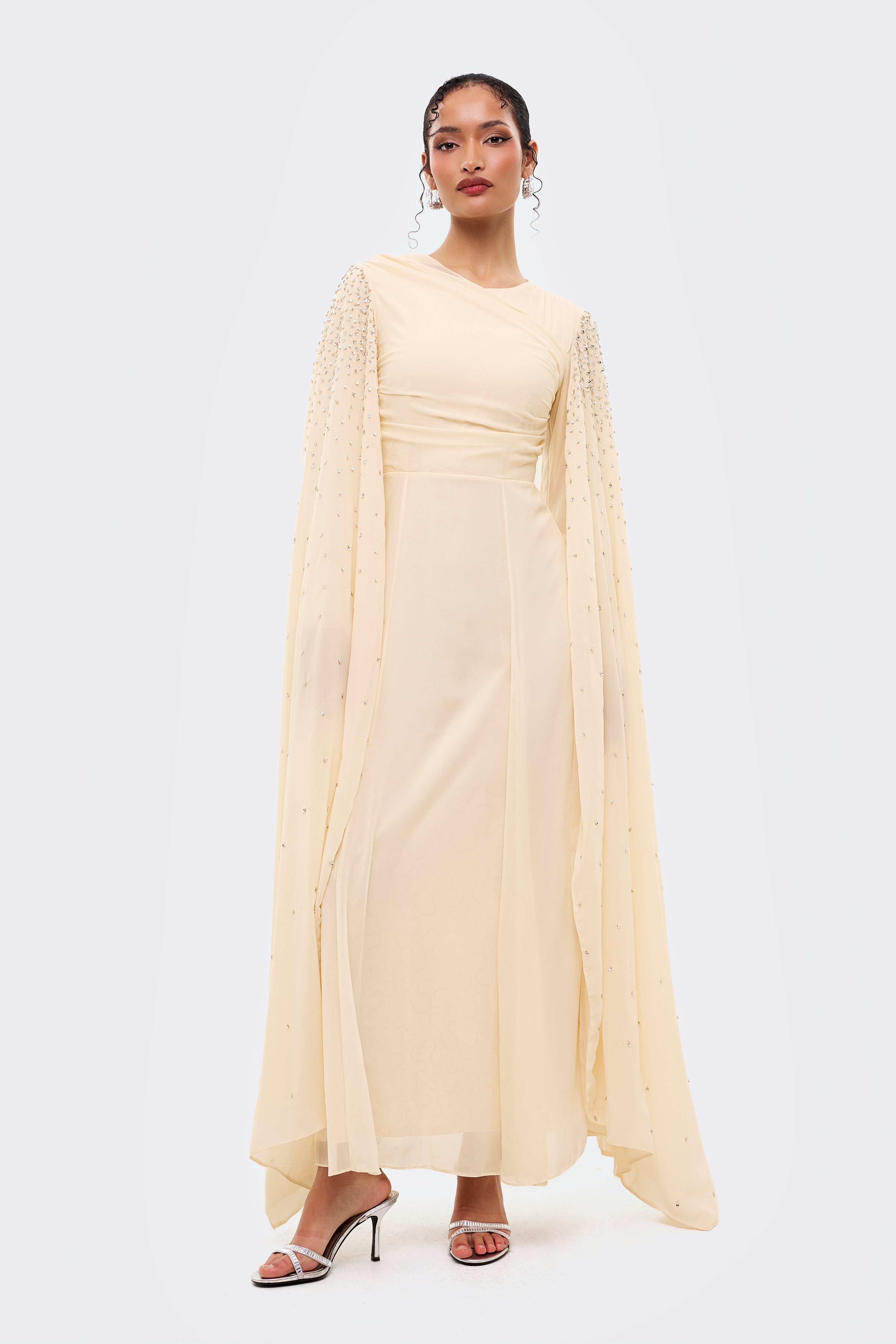 Woman wearing a light yellow dress with long sleeves on a white background