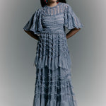 Woman wearing a blue patterned dress against a gray background