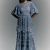 Woman wearing a blue patterned dress against a gray background