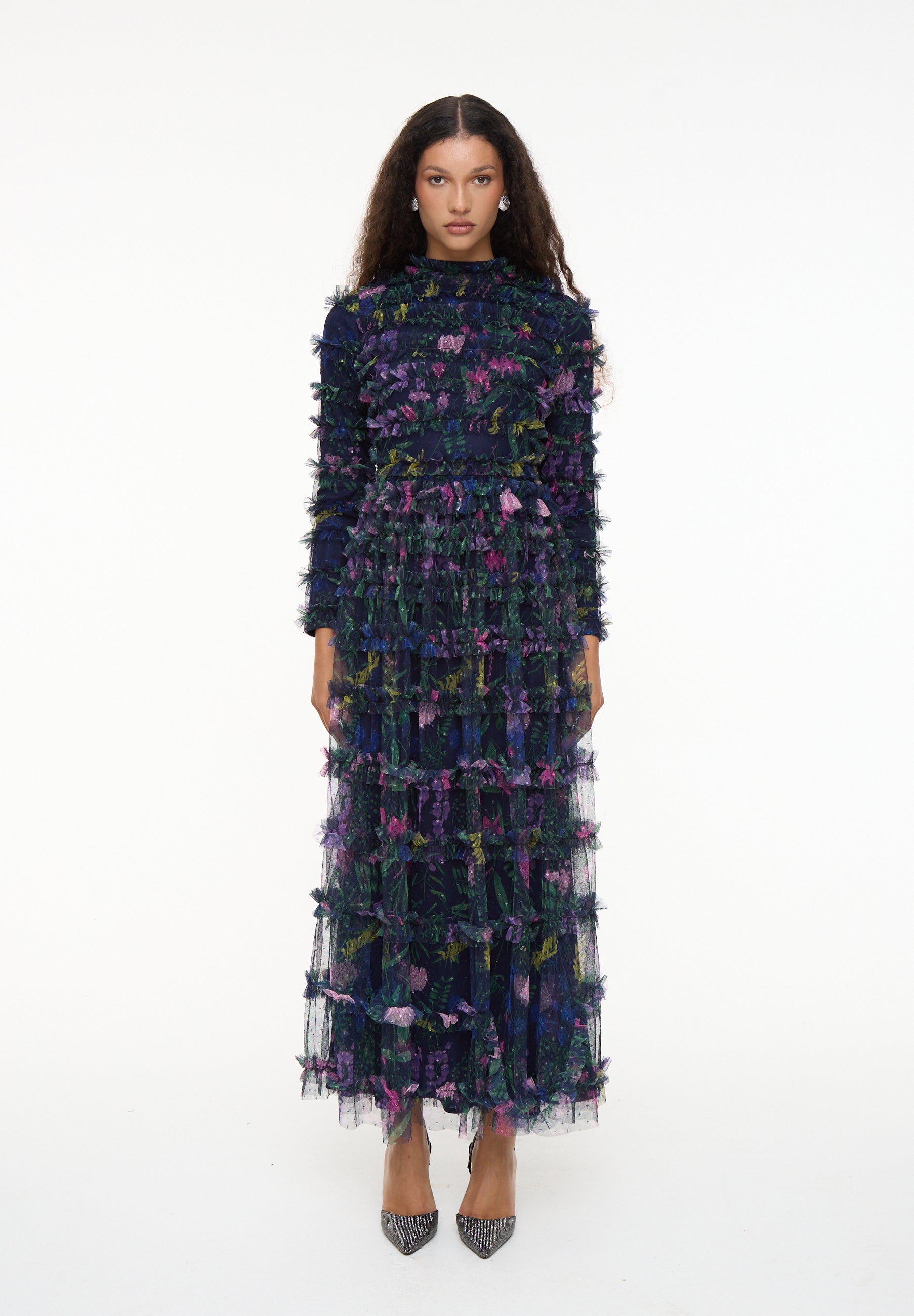 Woman wearing a long, dark blue dress with colorful floral patterns on a white background