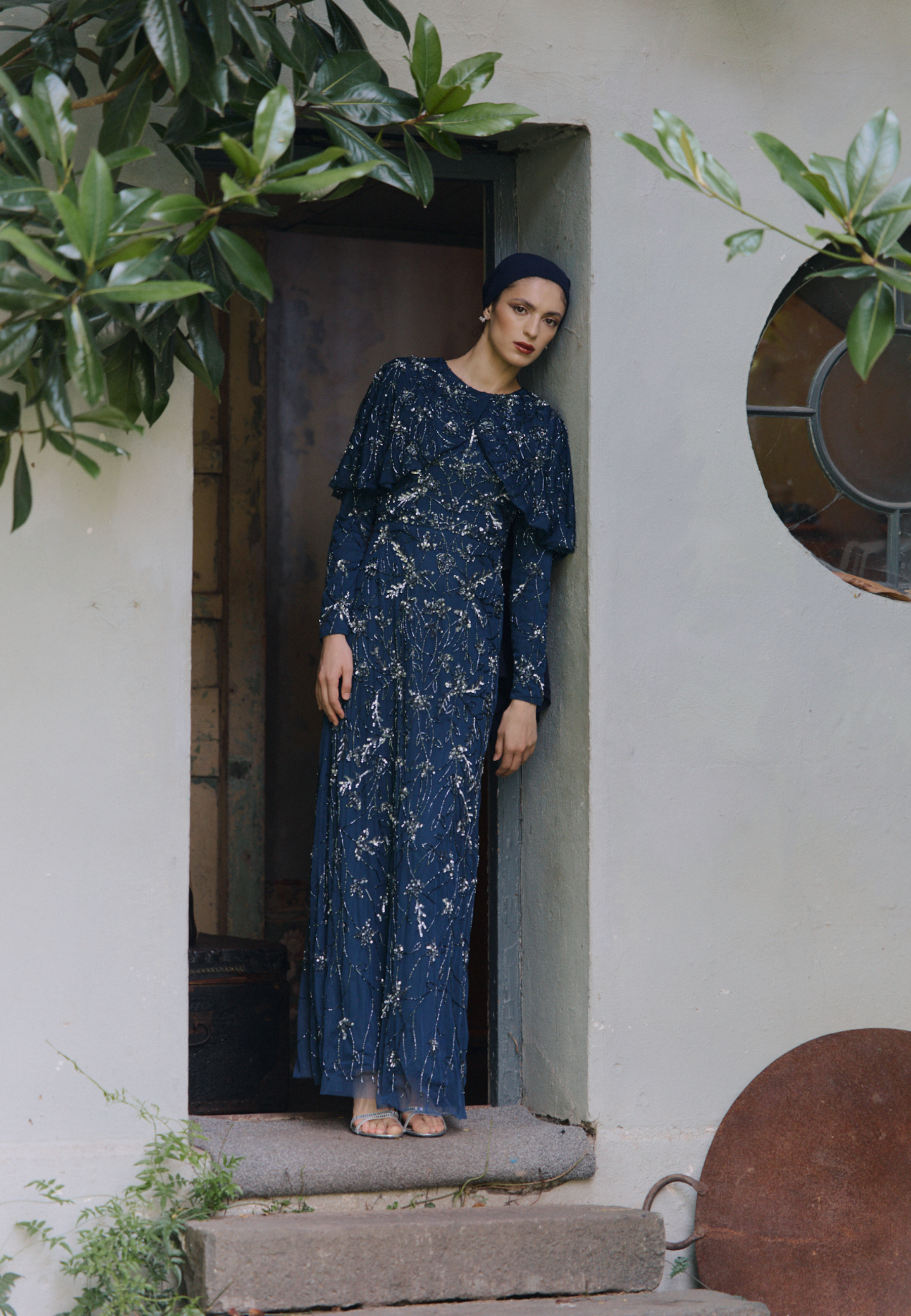 Woman in a blue sequin dress standing in a doorway, designed by MARYISA