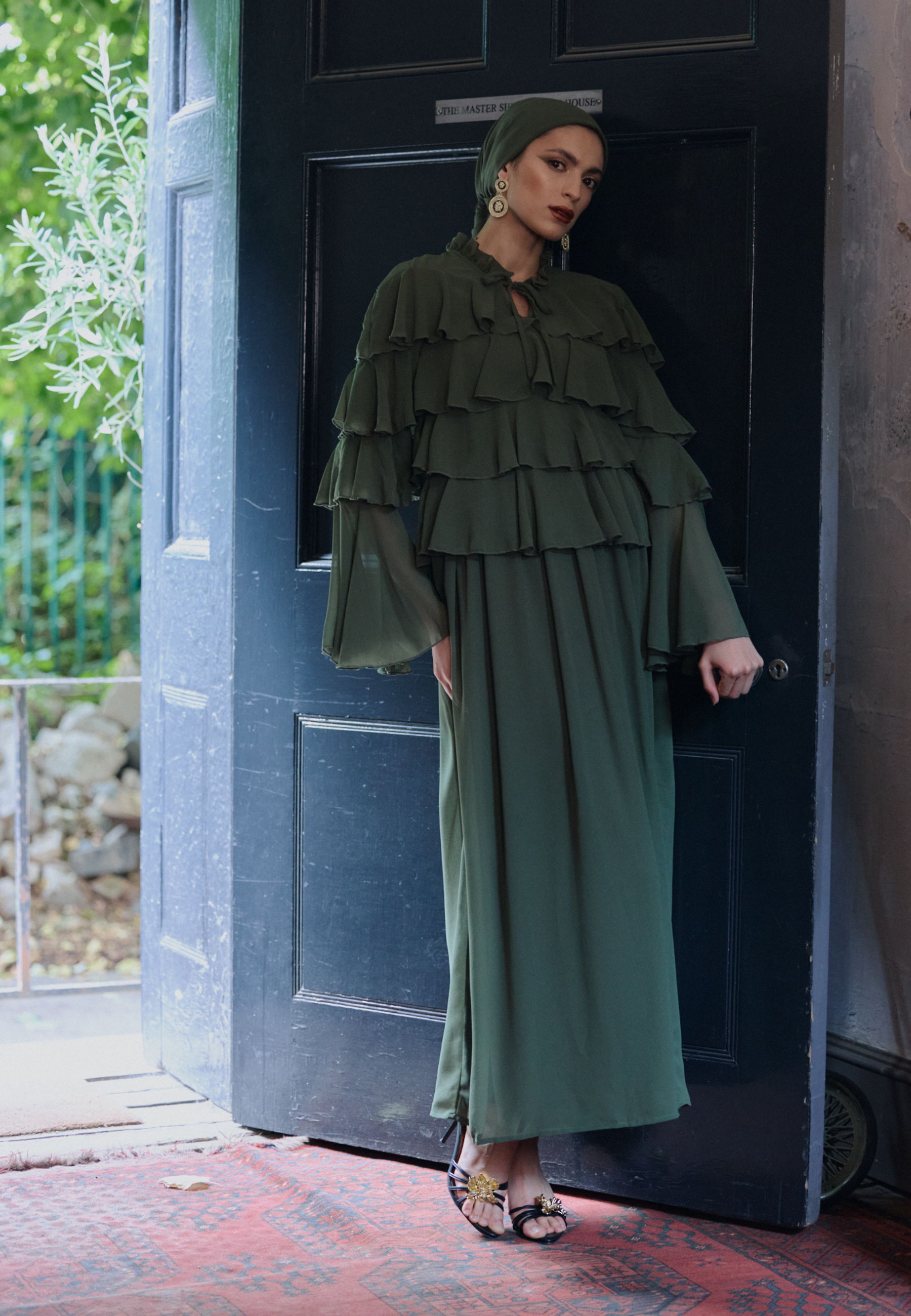 Woman in a green dress standing in front of a door, designed by Maryisa